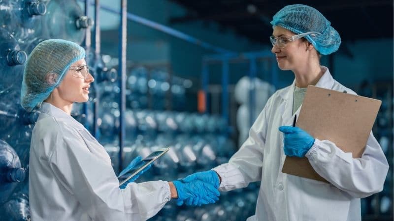 EPM Scientific Contract Recruitment Handshake Between Two Female Medical Production Workers