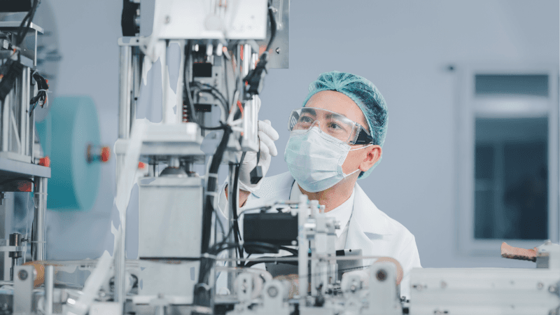 Male Scientist Overseeing Medical Device Factory's Machinery And Materials